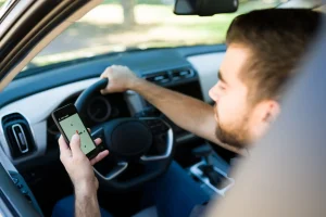 A man on his phone while driving his car.