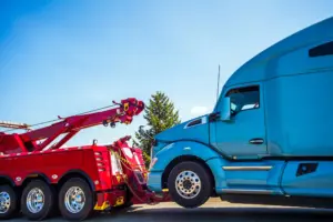 A red tow truck pulling a blue semi truck.
