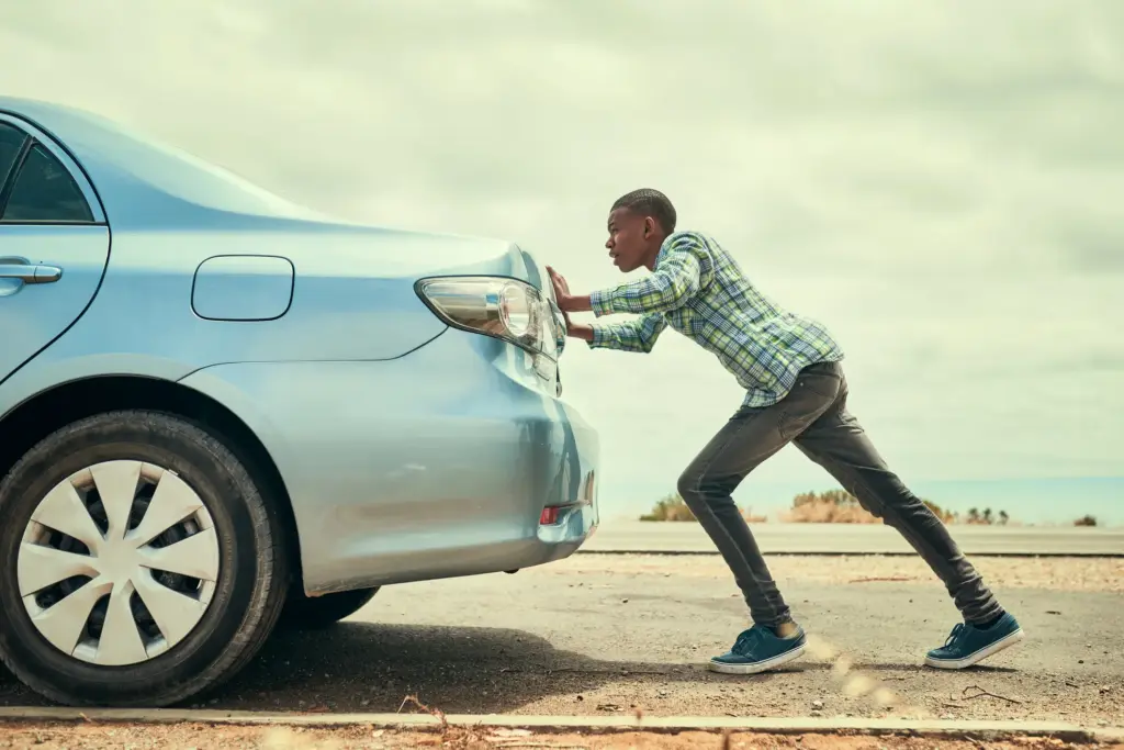 A man pushing a broken car.