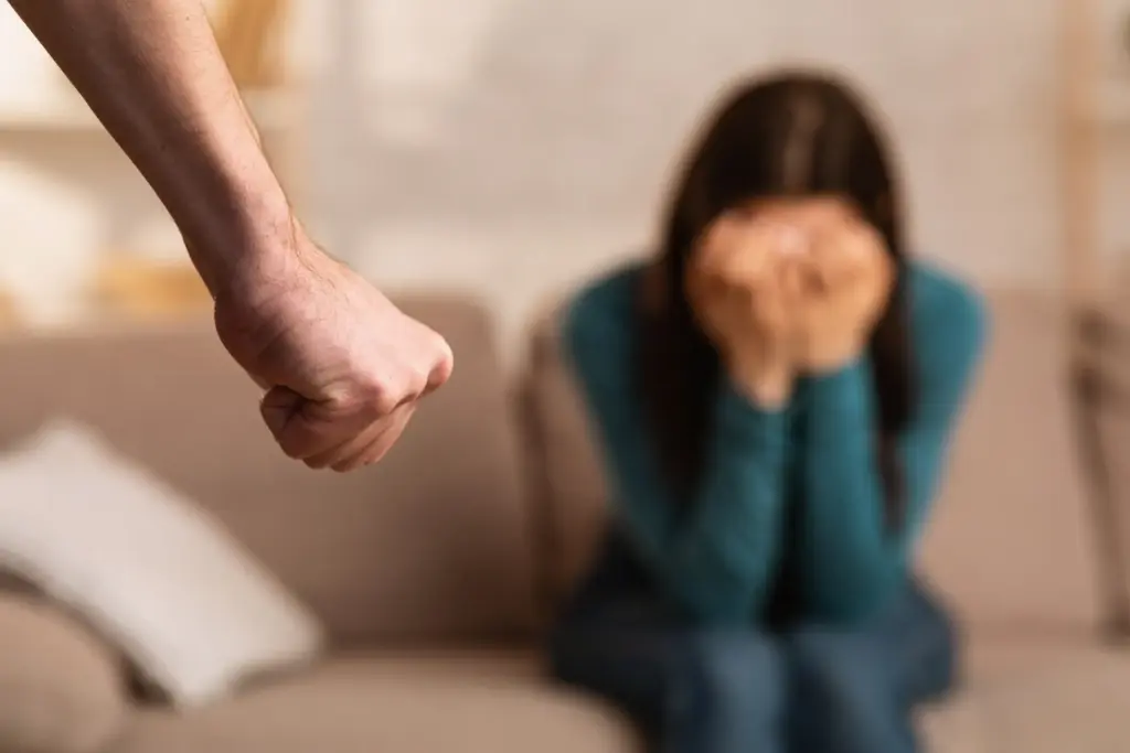 A man with a clenched fist approach a scared woman.
