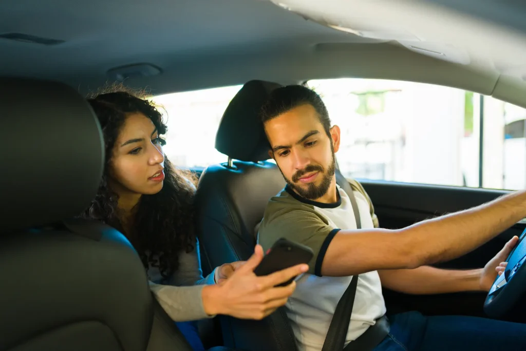 A woman showing her rideshare driver something on her phone.