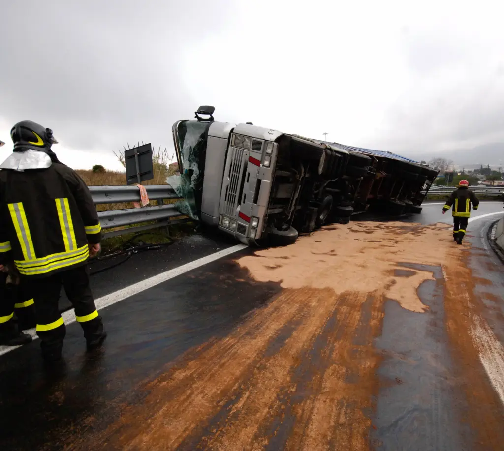 A truck rollover accident with a man looking at it from a distance.