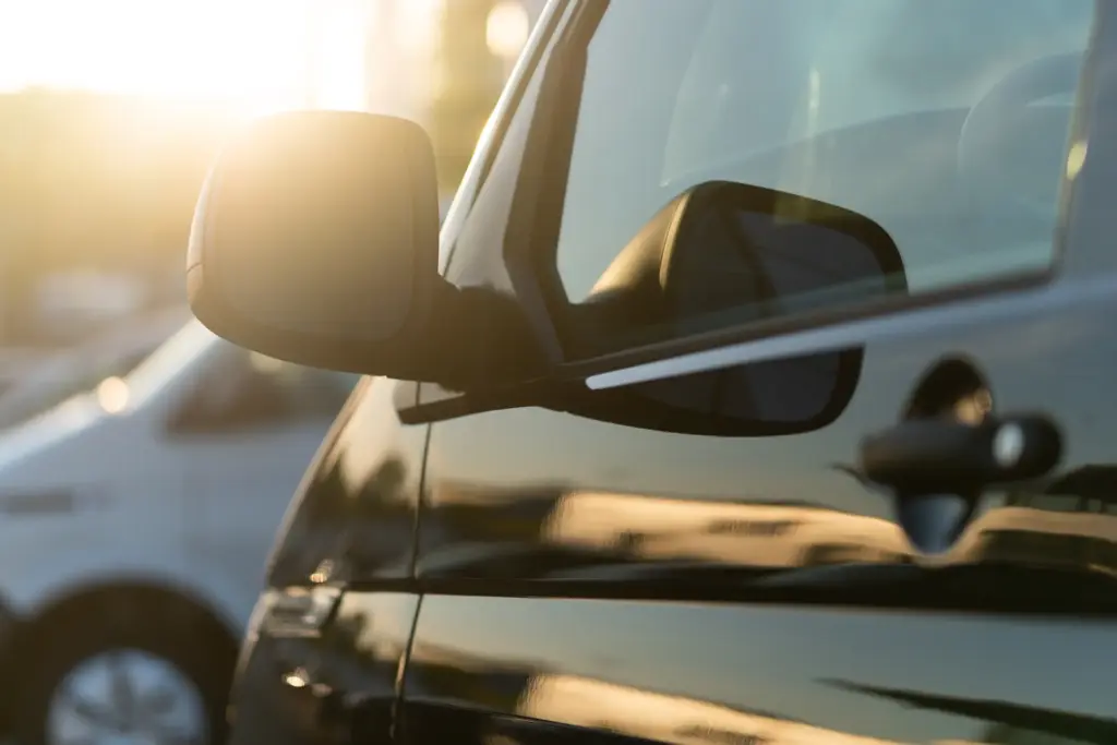 A car with tinted windows with the sun setting in the background.