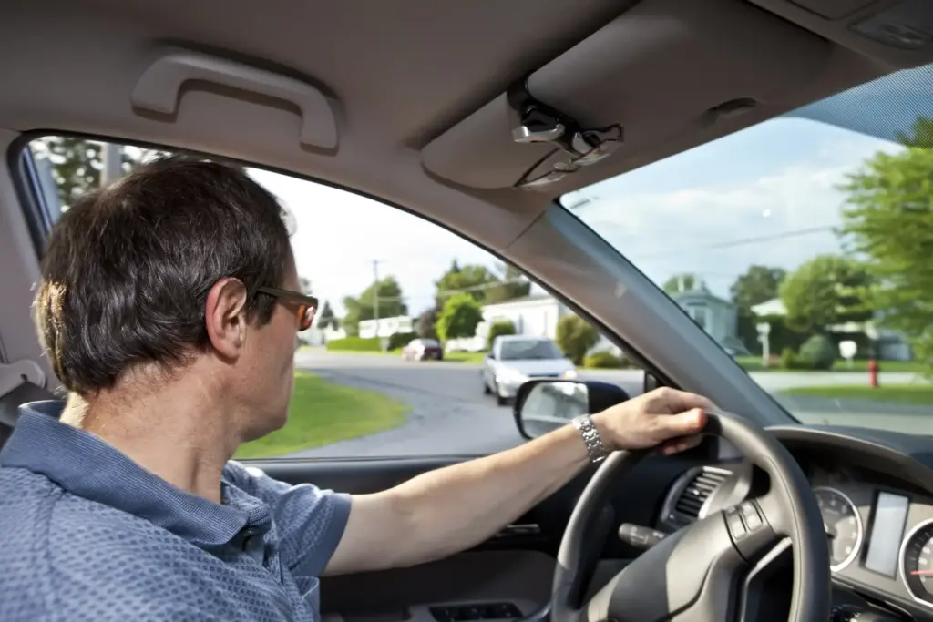 A man in a car looking both ways before he merges in an intersection.