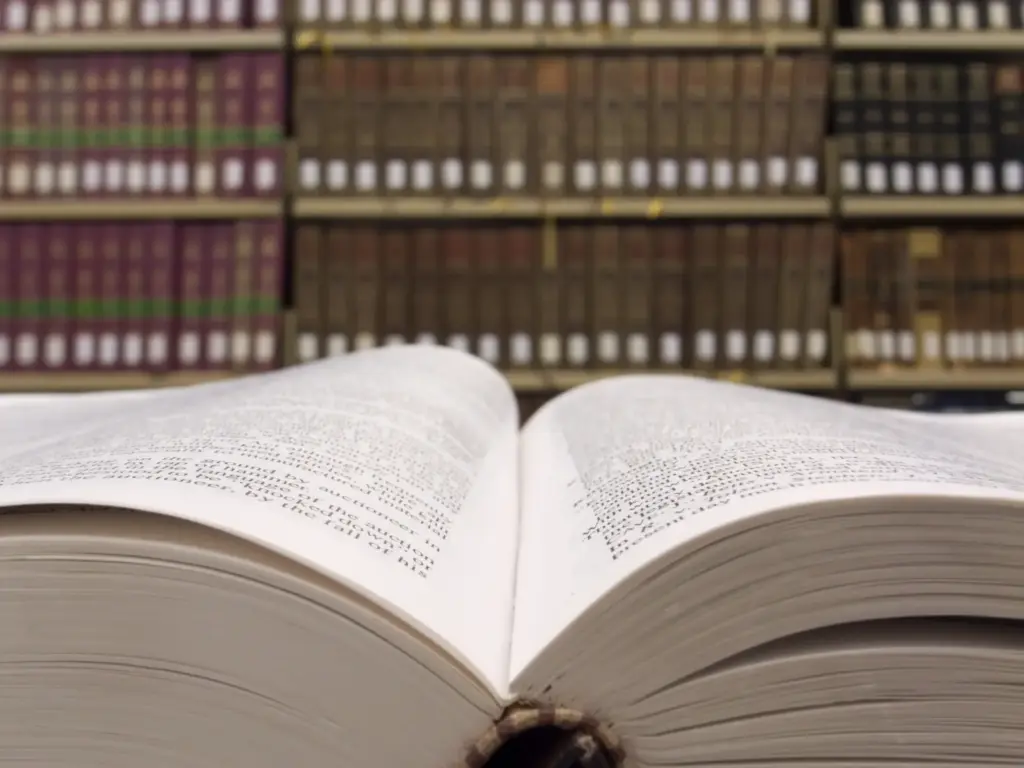 An open legal book with a bookshelf in the background.