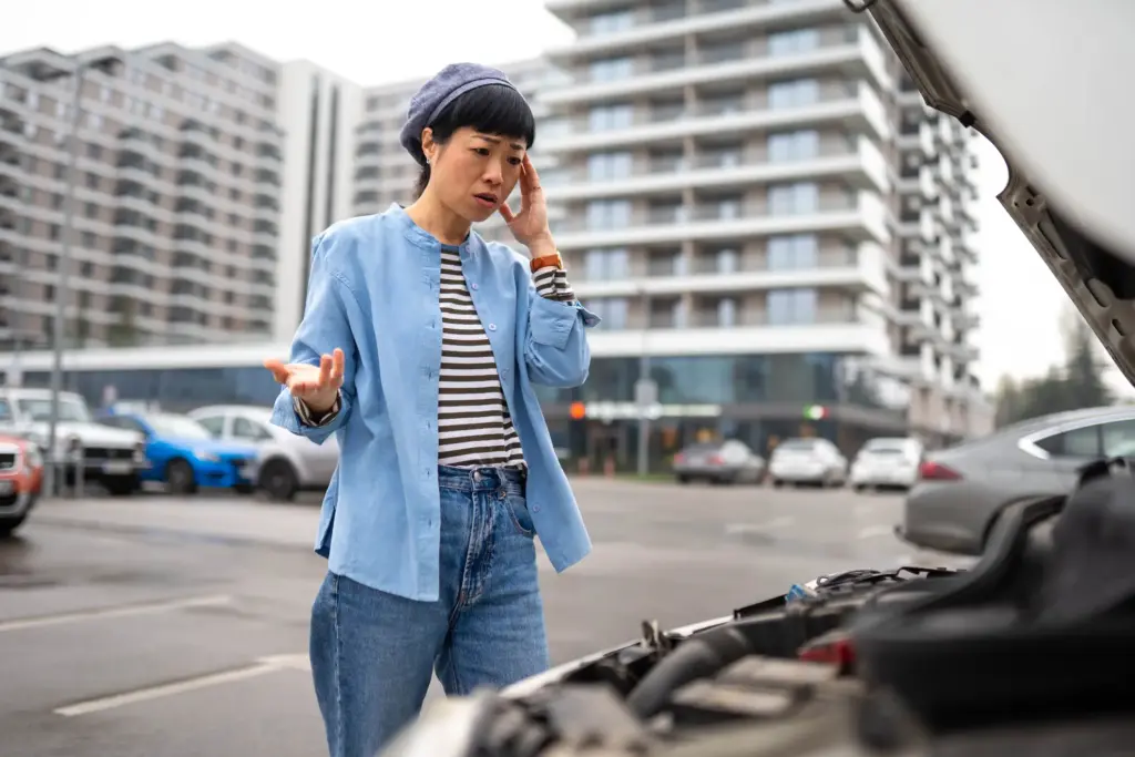 A woman arguing on the phone in front of her defective car.