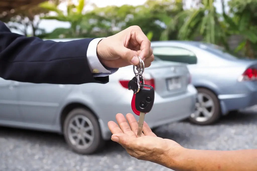 A person handing someone another pair of car keys.