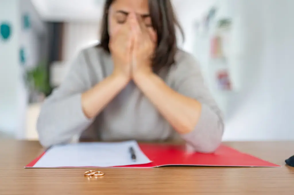 A woman looking stressed while trying to do some paperwork.