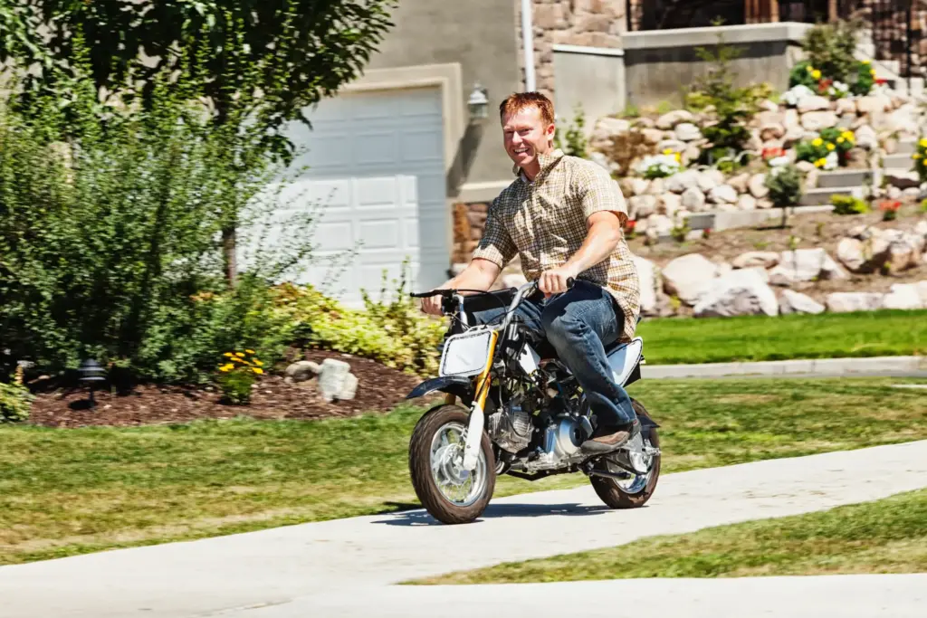 A man riding a mini bike on a sidewalk.