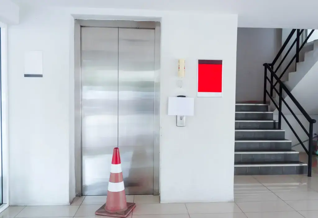 Broken elevator with a traffic cone in front.