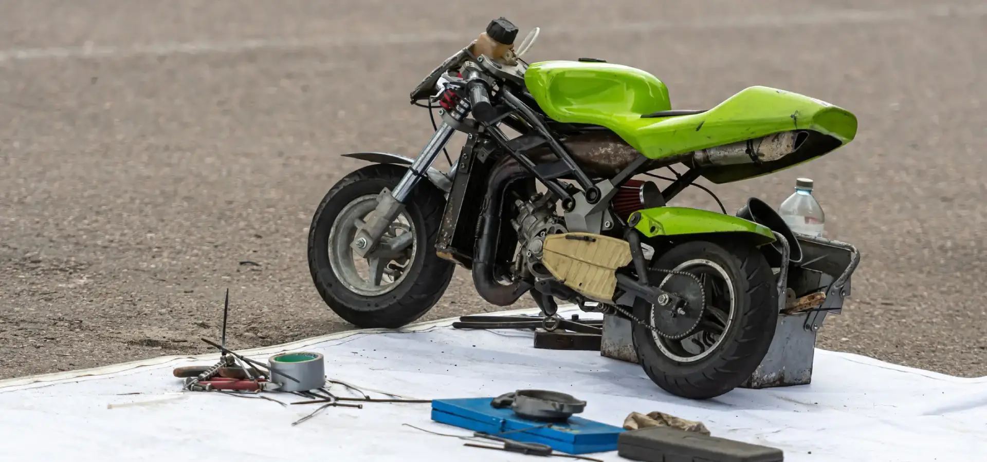 A green mini bike with tools surrounding it.