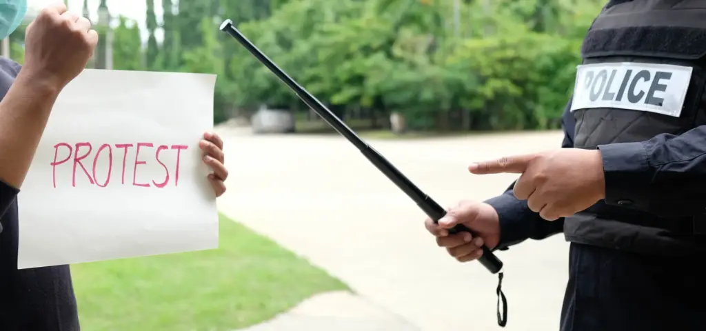 A police officer threatening a protestor with a police baton.