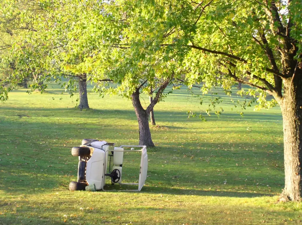 A tipped over golf kart on a golf course.