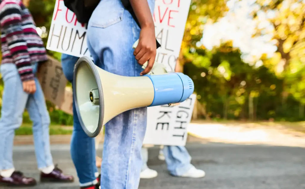 A person holding a megaphone with other protestors.
