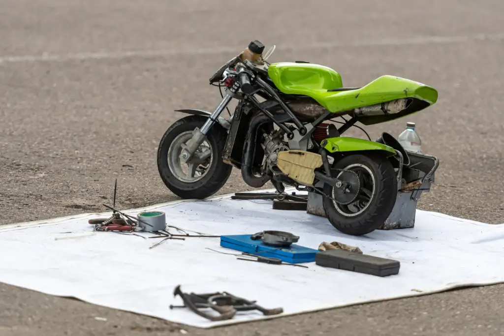 A green min bike with repair tools right next to it.