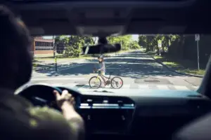A driver about to hit a biker crossing the street.