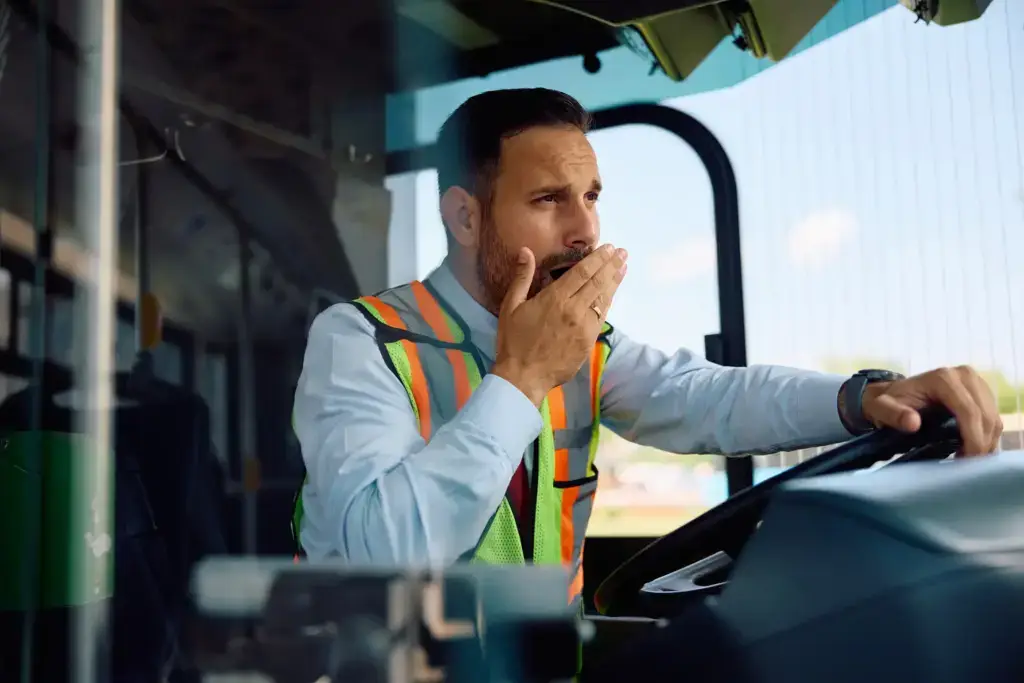 A yawning bus driver while behind the wheel.
