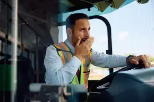 A yawning bus driver while behind the wheel.