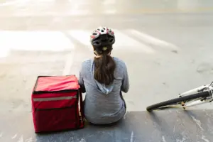 A food delivery biker resting on some stairs.