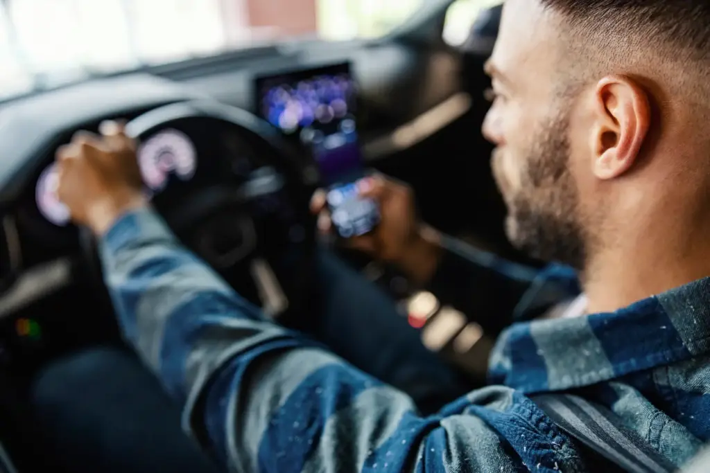 A man using a phone while driving his car.