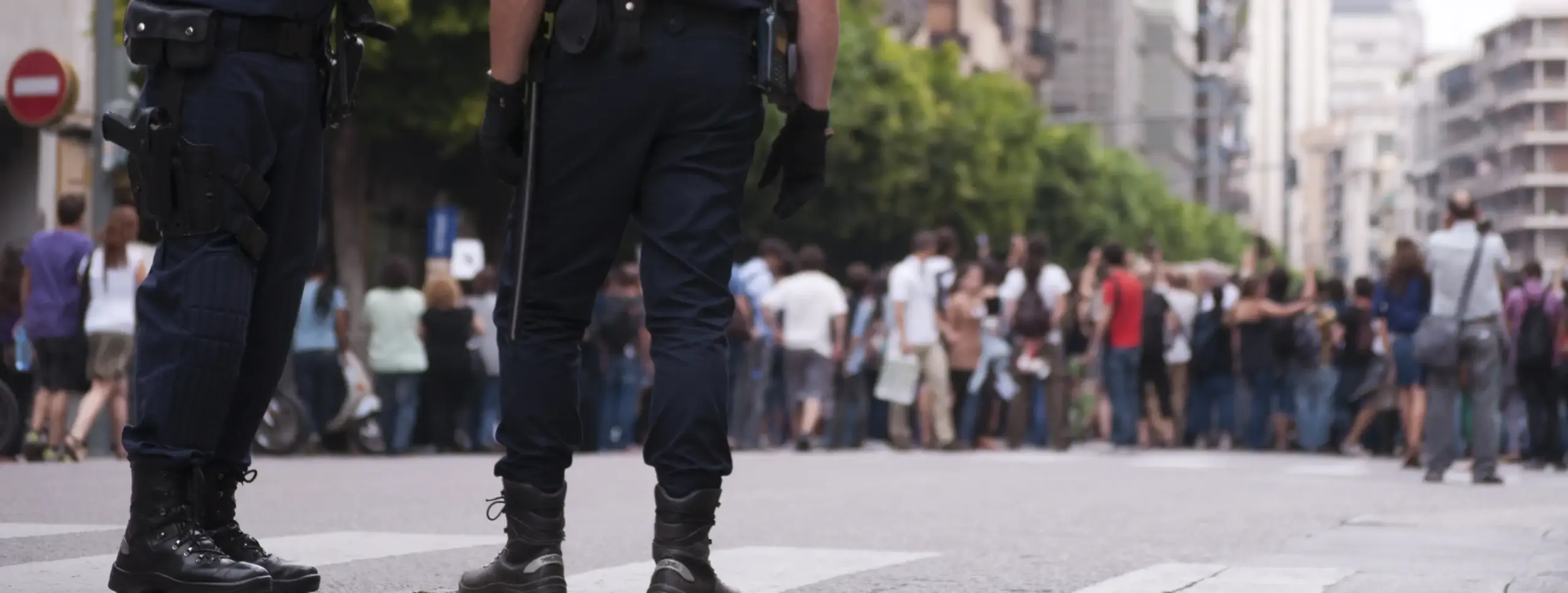 Two police officers watching a crowd of people. 