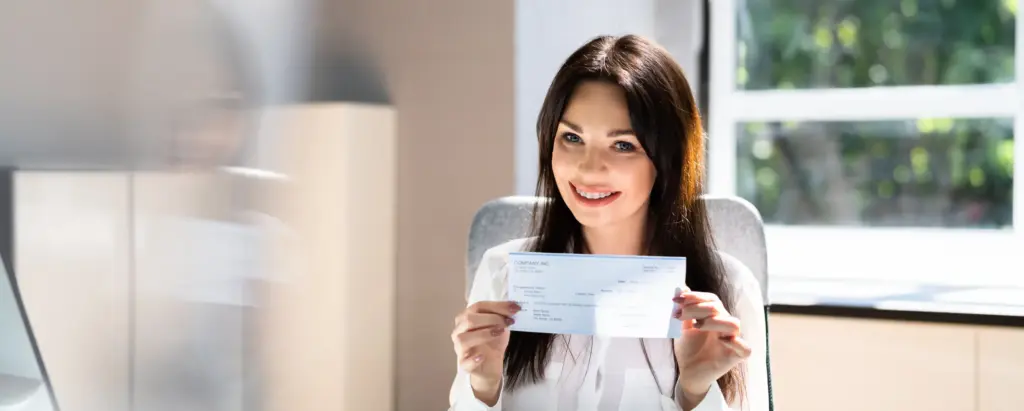 A woman smiling and holding a settlement check.