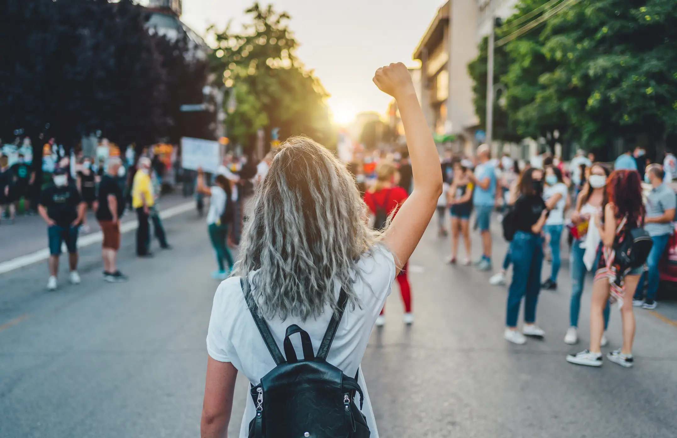 A woman marching the street with her fist up in the air.
