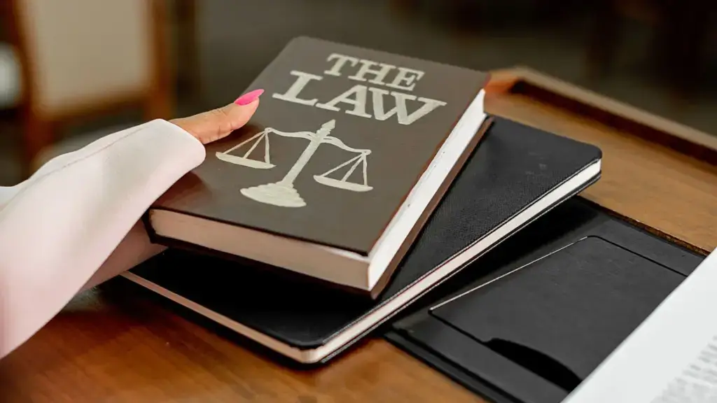A woman grabbing a law book from a table.
