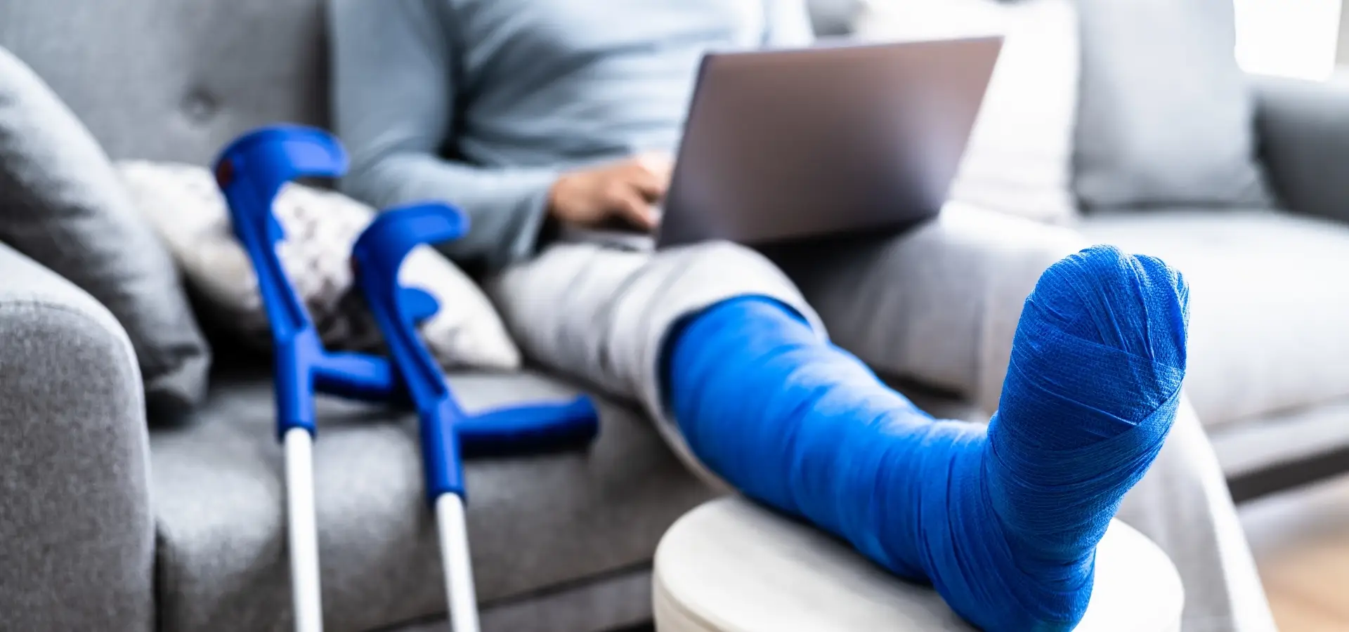 A man with a broken leg looking to hire a lawyer on a laptop.