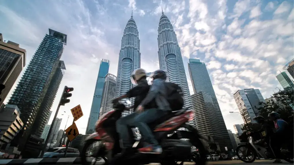 Two people riding a motorcycle in a city.