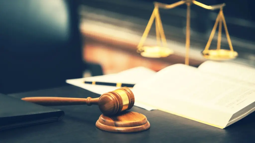 A gavel, scale, and book on a table.