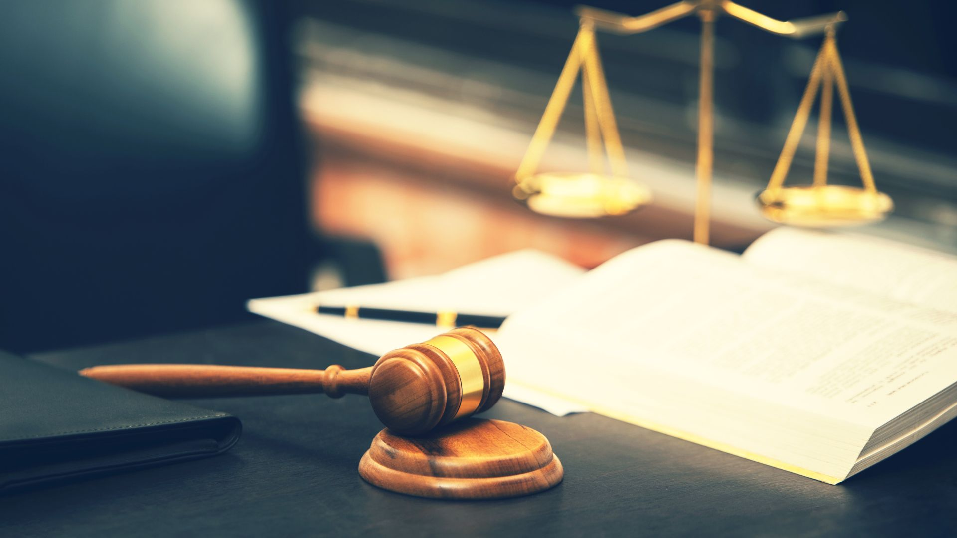 A gavel, scale, and book on a table.