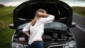 A woman looking confused at her car's engine.