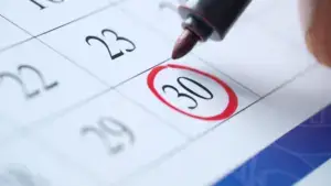 A person circling the 30th on a calendar.
