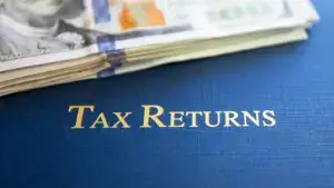 Tax Return folder with a stack of hundreds on top. 