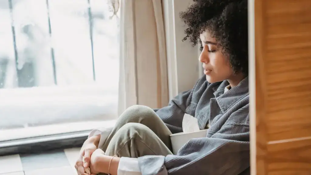 A depressed woman sitting on the floor.