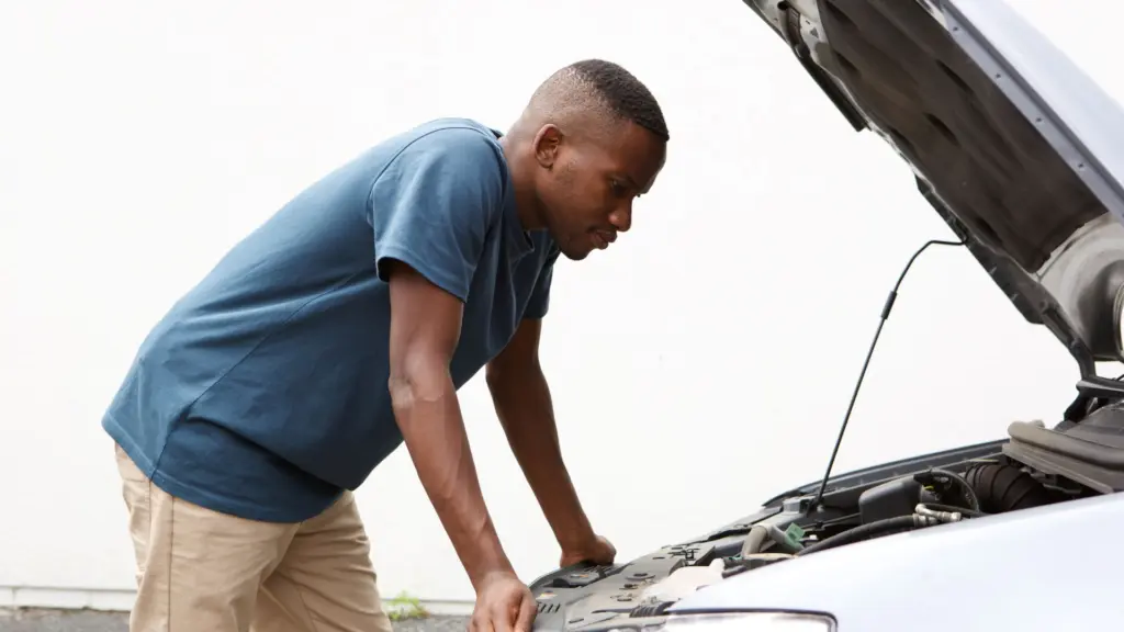 A man looking at his car engine, confused.