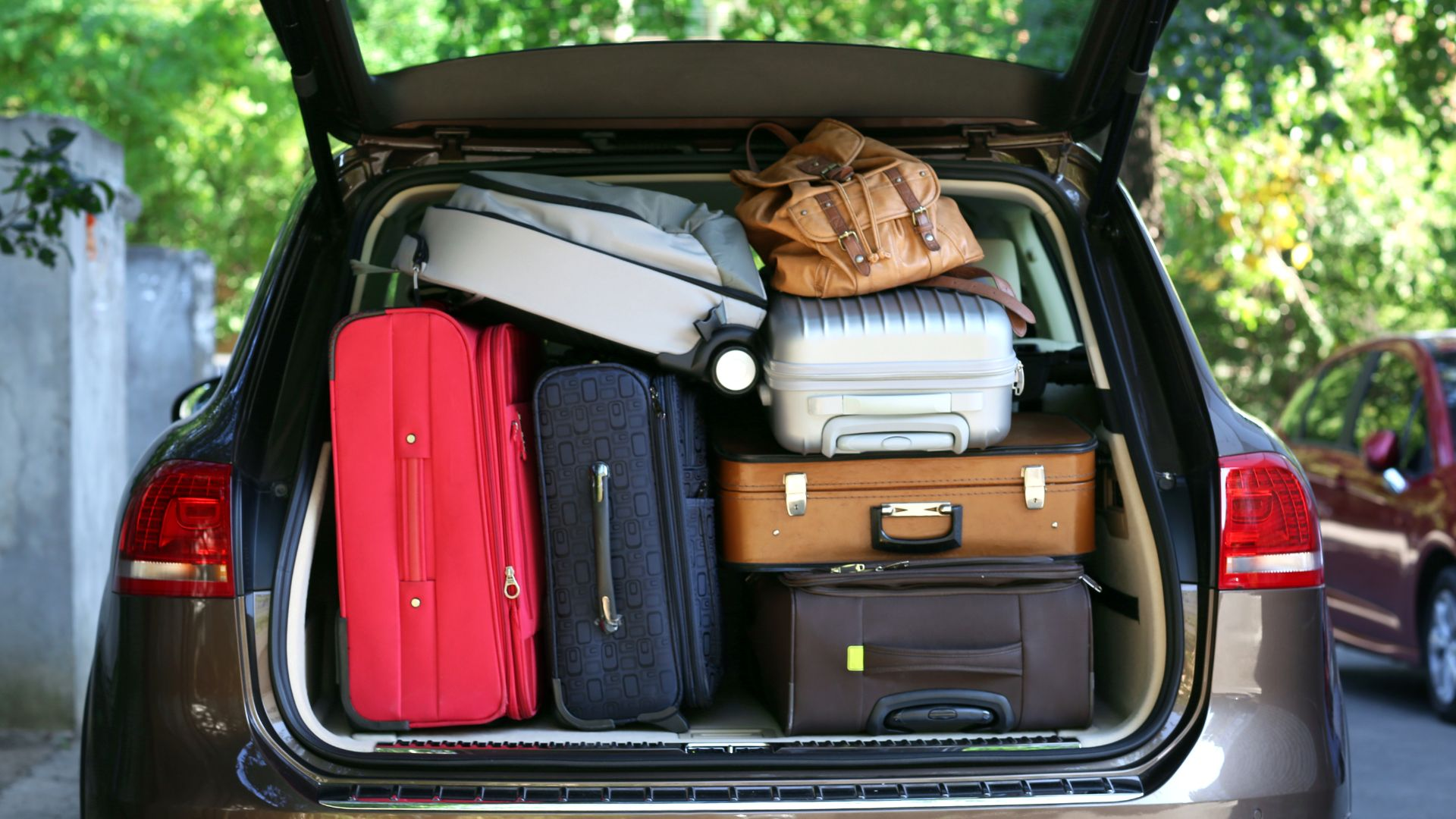 An overloaded trunk filled with suitcases.