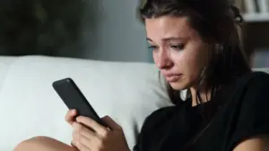 A sad woman looking at her phone. 