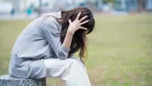 A sad woman sitting on a bench at a park.