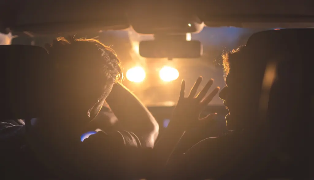 A driver and their passenger being blinded by bright car lights.