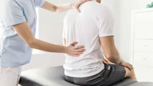 A doctor assessing a man's lumbar injury.