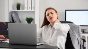A woman at work holding her neck in pain.