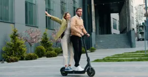A couple riding one electric scooter.