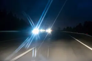 Cars from the opposite end of a highway speeding down with their highbeams on. 