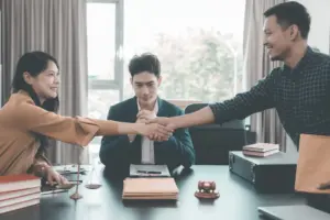Two people shaking hands while a meditator in the middle is looking satisfied. 