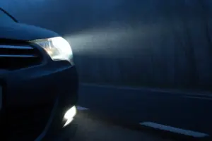 A car using their high beams in a dark foggy area. 