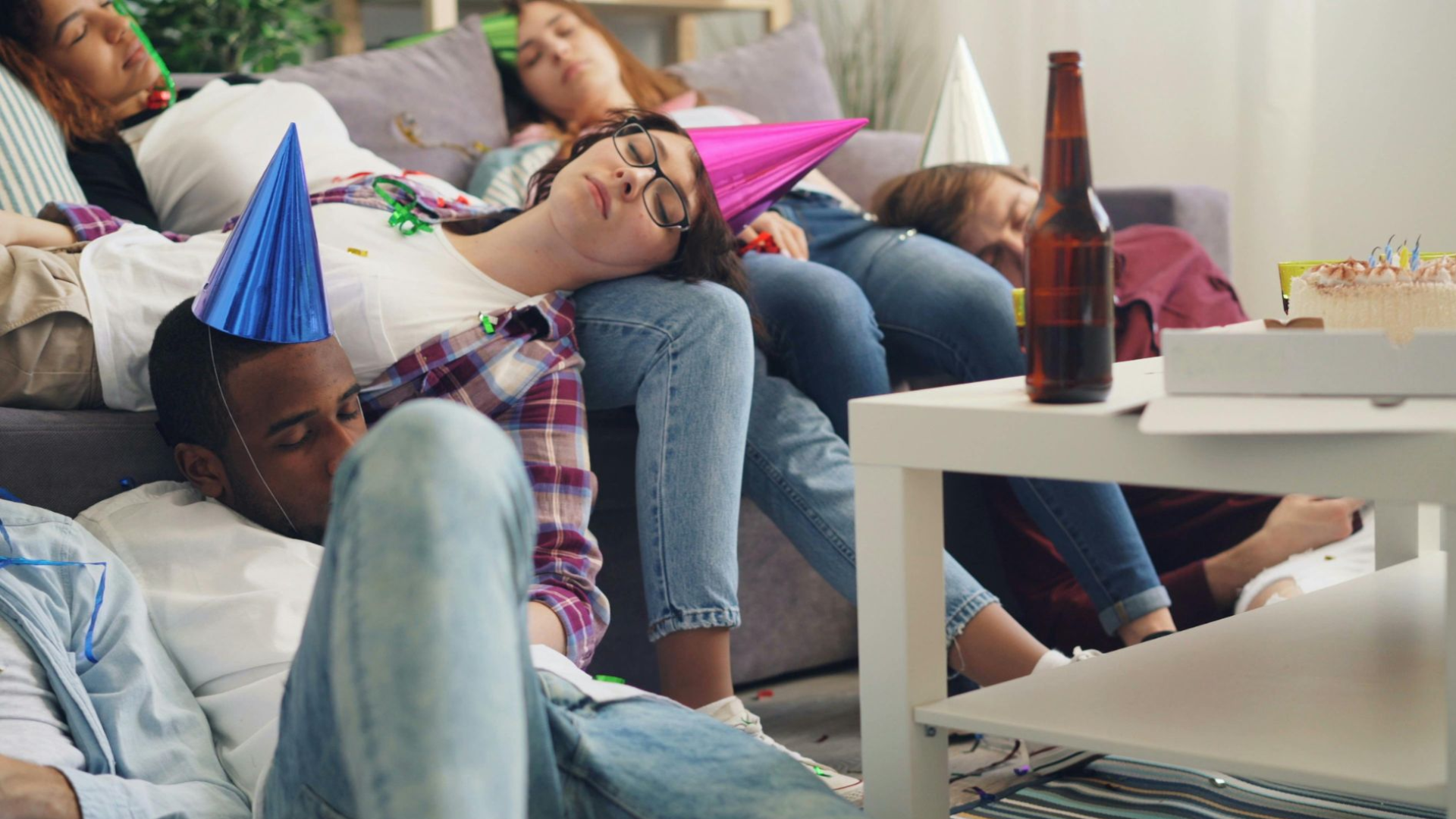 Several people sleeping in the living room after a holiday party.