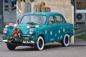 A blue vintage car with Christmas lights and decorations on it. 