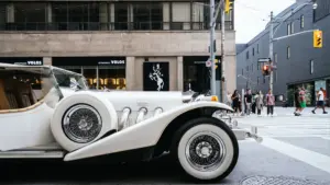 A white classic car driving through the city.